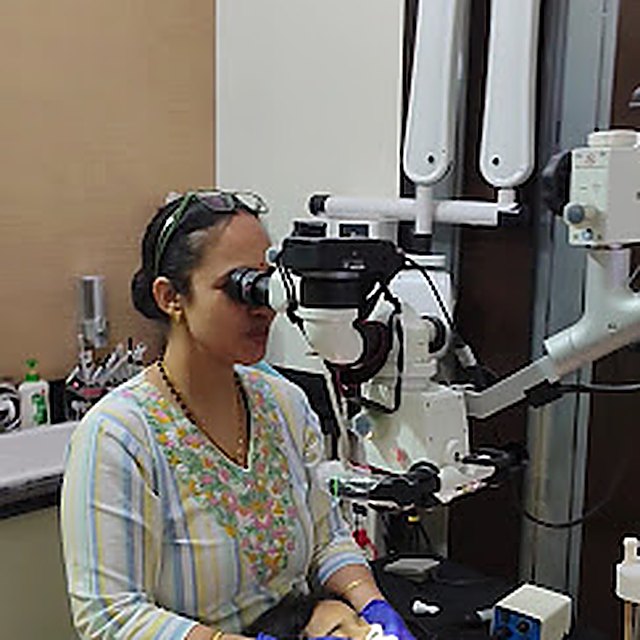 Dr. Sapna Sharma working under a dental microscope in Rohtak